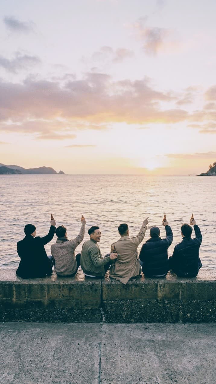 夕日の海辺で乾杯する仲間たち